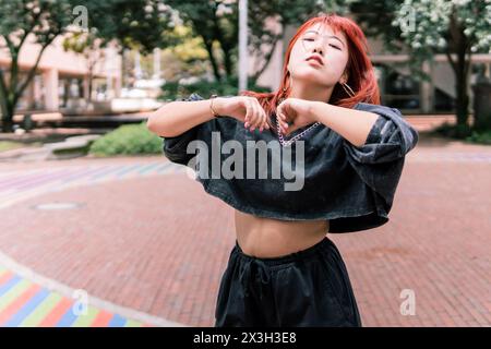 Gioiosa donna coreana che balla liberamente su un colorato marciapiede urbano Foto Stock
