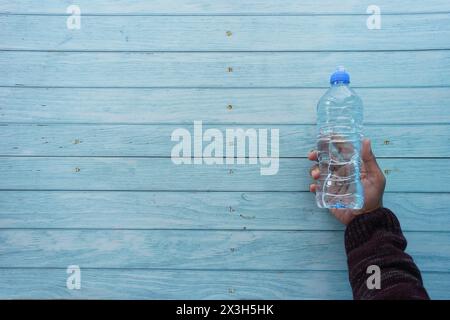 vista dall'alto della mano che regge una bottiglia d'acqua in plastica Foto Stock