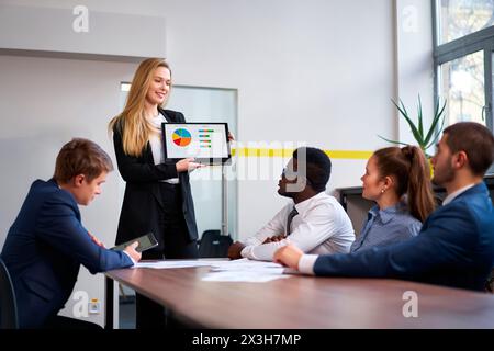 Il CEO donna presenta un grafico colorato sul laptop ai colleghi multietnici durante la riunione. Dipendenti maschi e donne si impegnano in discussioni strategiche, africane Foto Stock