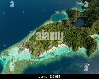 Spiaggia di Banul con sabbia bianca e barche sull'acqua cristallina. Lago nero a Coron, Palawan. Filippine. Foto Stock