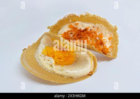 Primo piano di Khanom Bueang o frittelle croccanti tailandesi, con Foi Thong (tuorlo d'uovo dolce) e condimenti al cocco grattugiato su panna d'uovo Foto Stock