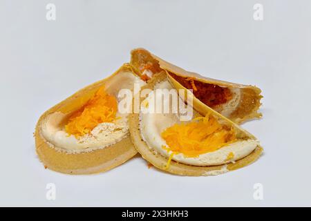 Khanom Bueang o pancake croccanti thailandesi, conditi con fari Thong (tuorlo d'uovo dolce) (davanti) e cocco grattugiato (dietro) sulla panna d'uovo Foto Stock