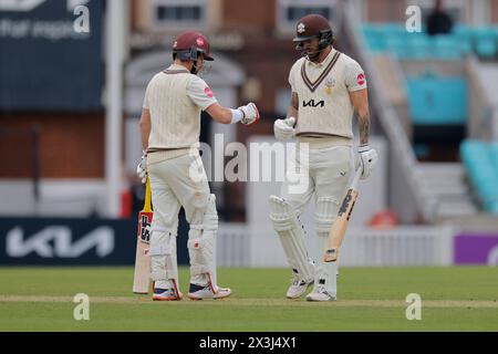 Londra. 27 aprile 2024. Rory Burns (17 Surrey Captain) e Jordan Clark (16 Surrey)pugno durante il secondo giorno della partita County Championship Division One tra Surrey e Hampshire al Kia Oval. Crediti: Matthew Starling / Alamy Live News Foto Stock