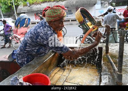 Un autista di risciò che si lava il viso con acqua in un gasdotto lungo la strada durante le ondate di caldo a Dacca, Bangladesh, il 27 aprile 2024 Credit: Mamunur Rashid/Alamy Live News Foto Stock