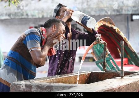 Un autista di risciò che si lava il viso con acqua in un gasdotto lungo la strada durante le ondate di caldo a Dacca, Bangladesh, il 27 aprile 2024 Credit: Mamunur Rashid/Alamy Live News Foto Stock