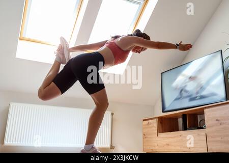 Corsi di allenamento online. Atletica che si allena a casa con lezioni di video sport in TV. Foto Stock