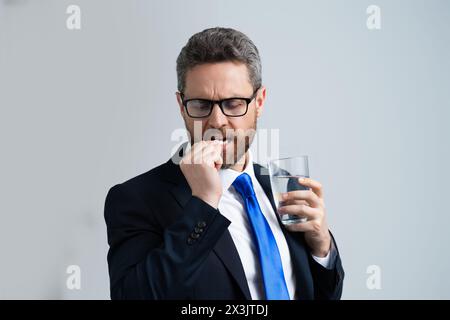 Uomo d'affari sottolineato in tuta che ha mal di testa. L'uomo d'affari stanco lavora fuori orario e ha mal di testa. L'uomo iperlavorato soffre di mal di testa. Emicrania Foto Stock