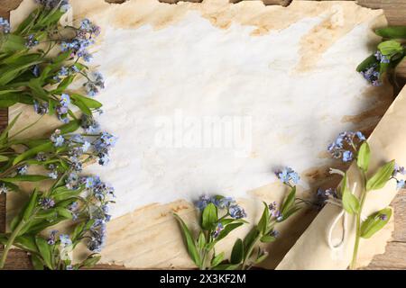Bellissimi fiori e fogli di carta pergamena vecchia sul tavolo, vista dall'alto Foto Stock