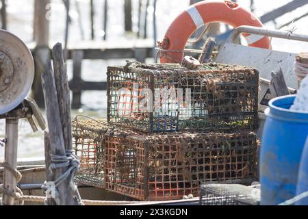 Una barca con un container blu e due gabbie di pesca arrugginite - trappola per granchi Foto Stock