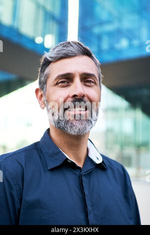 Uomo d'affari maturo dai capelli grigi che sorride alla macchina fotografica con un atteggiamento positivo nella camicia vestito. Foto Stock
