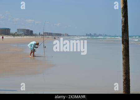 Un pescatore da surf viene cacciato sopra la canna da pesca sul bordo dell'oceano, Ponce Inlet, Jetty Beach, Florida. Foto Stock