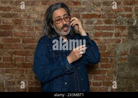 Uomo latino-americano (44) con lunghi capelli grigi che parla al suo cellulare. Concetto di tecnologia Foto Stock