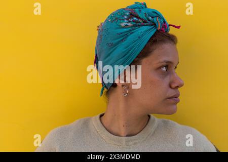 Afro donna latinoamericana (34) con occhi verdi, velo e isolata su sfondo giallo con la testa girata verso il lato sinistro. Foto Stock