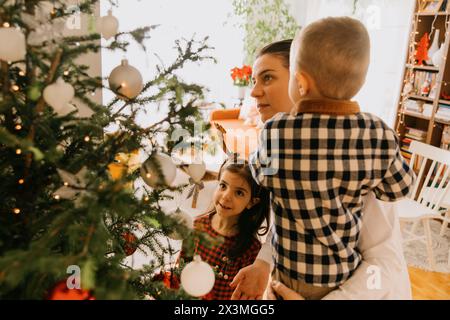 La famiglia ama le vacanze, decorando insieme l'albero di Natale Foto Stock