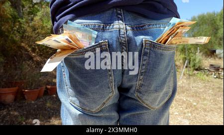 banconote da 50 e 20 euro che sporgono dalle tasche di una persona che indossa jeans blu Foto Stock