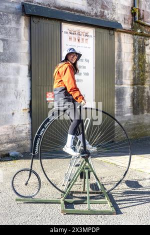 Turista femminile in bicicletta da corsa a pagamento nel distretto vittoriano di Oamaru, Harbour Street, Oamaru, Otago, South Island, nuova Zelanda Foto Stock