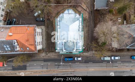 Fotografia con drone di una vecchia chiesa in fase di ristrutturazione tra condomini in una città durante il sole del giorno primaverile Foto Stock