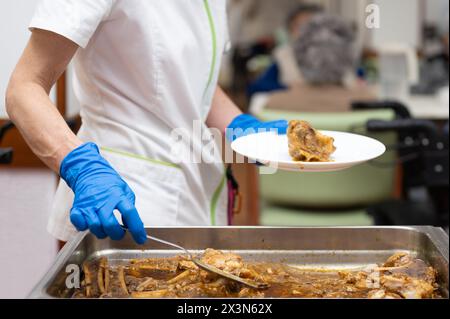 Primo piano di un infermiere che serve cibo a persone anziane nella casa di cura. Fotografia di alta qualità Foto Stock