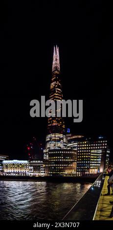 Vista notturna del grattacielo di Londra The Shard con il cielo completamente buio e gli edifici sotto con le finestre illuminate in molti colori. Foto Stock
