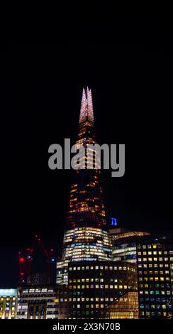 Vista notturna del grattacielo di Londra The Shard con il cielo completamente buio e gli edifici sotto con le finestre illuminate in molti colori. Foto Stock