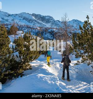 un gruppo di escursionisti attraversa una foresta innevata con le racchette da neve Foto Stock