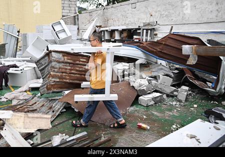 (240428) -- GUANGZHOU, 28 aprile 2024 (Xinhua) -- Un uomo rimuove i detriti dopo un tornado nel villaggio di Guangming della città di Zhongluotan del distretto di Baiyun, Guangzhou, provincia del Guangdong della Cina meridionale, 28 aprile 2024. Cinque persone sono state uccise e altre 33 ferite da un forte tornado che ha colpito Guangzhou, la capitale della provincia del Guangdong della Cina meridionale, sabato pomeriggio, hanno detto le autorità locali. Il tornado colpì Zhongluotan Town nel distretto di Baiyun intorno alle 15:00, mentre la stazione meteorologica nel villaggio di Liangtian, a circa 2,8 chilometri dal punto di ritrovo del tornado, il regist Foto Stock