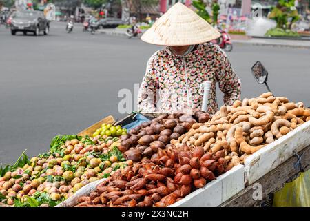 Una donna che indossa abiti tradizionali vietnamiti vende frutta e verdura sulla strada della città. I venditori ambulanti di da Lat Vietnam. Donna vietnamita Foto Stock