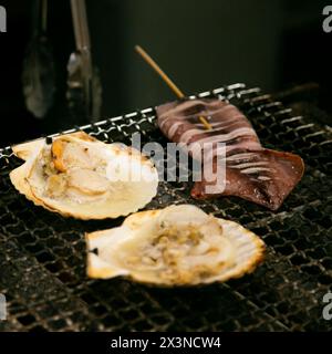 Guscio di pesce e pesce cucinati su una griglia al mercato del pesce di Osaka in Giappone. Foto Stock