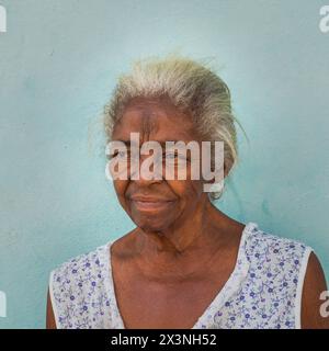 Ritratto della testa e delle spalle di una signora fuori dalla parte anteriore di una casa nelle strade secondarie della città vecchia, Trinidad, Cuba. Foto Stock