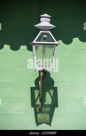 Vecchia lampada di vetro appesa a una parete che crea un motivo gettando un'ombra sul muro dietro, nelle strade secondarie della città vecchia, Trinidad, Cuba. Foto Stock