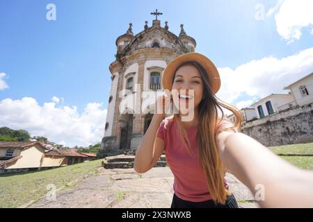 Selfie a Ouro Preto, Brasile. Giovane donna turistica che si fa autoritratto con la chiesa di nostra Signora del Rosario a Ouro Preto destinazione turistica Foto Stock