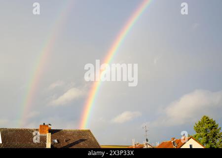 Arcobaleno sopra la casa dopo una tempesta con le nuvole in città. Vista panoramica del bellissimo tramonto. Foto Stock