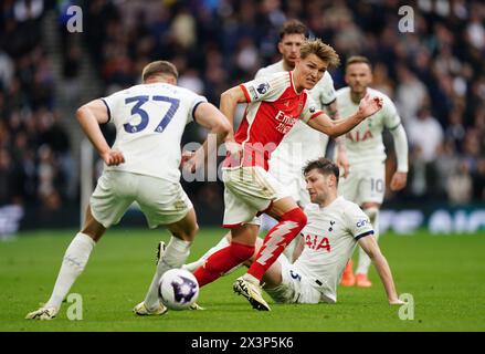 Martin Odegaard (centro) dell'Arsenal batte il pallone contro Micky van de Ven (a sinistra) del Tottenham Hotspur durante la partita di Premier League allo stadio Tottenham Hotspur di Londra. Data foto: Domenica 28 aprile 2024. Foto Stock