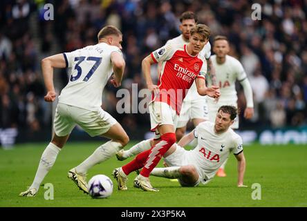 Martin Odegaard (centro) dell'Arsenal batte il pallone contro Micky van de Ven (a sinistra) del Tottenham Hotspur durante la partita di Premier League allo stadio Tottenham Hotspur di Londra. Data foto: Domenica 28 aprile 2024. Foto Stock