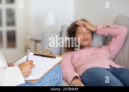 Terapeuta non riconoscibile che ascolta la donna cliente, prende appunti Foto Stock