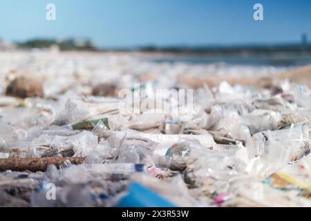 Primo piano di una spiaggia inquinata da rifiuti di plastica bottiglie di plastica sporche vuote Foto Stock