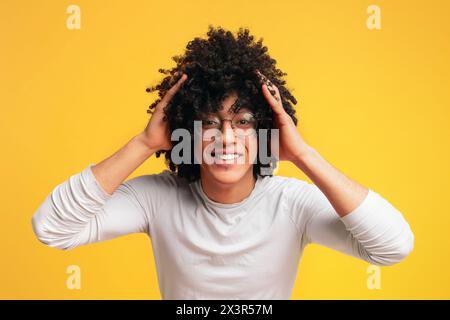 Sorpreso giovani curly-dai capelli ragazzo nero stringendo la sua testa, Foto Stock