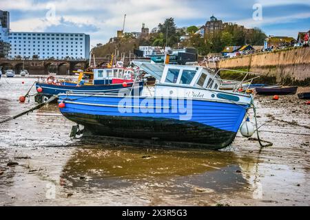 Barche da pesca ormeggiate nel porto di Folkestone con la bassa marea con il Grand Burstin Hotel sullo sfondo Foto Stock