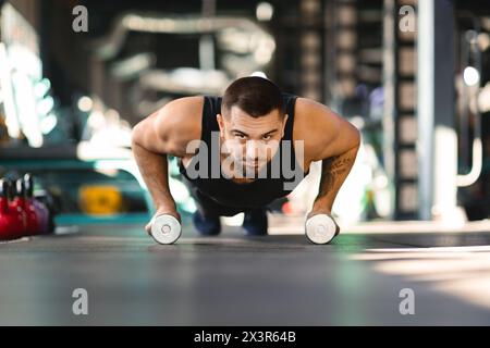 Uomo che fa Push Up con due Dumbbells Foto Stock