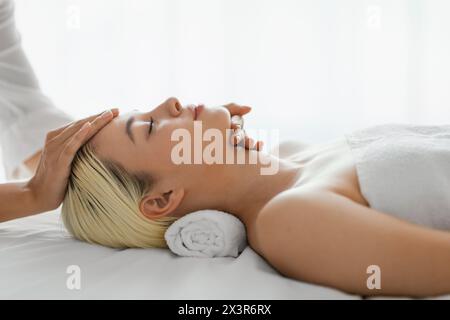 Donna che riceve un massaggio facciale da Woman Therapist Foto Stock