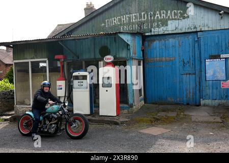 Motociclista su una motocicletta costruita su misura in un vecchio garage in disuso a molto Wenlock, nello Shropshire Foto Stock