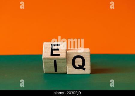 Icona EI o EQ. Un blocco di legno con una parola che mostra sia il simbolo dell'intelligenza emotiva che il quoziente emotivo. Bellissimo sfondo verde e arancione Foto Stock