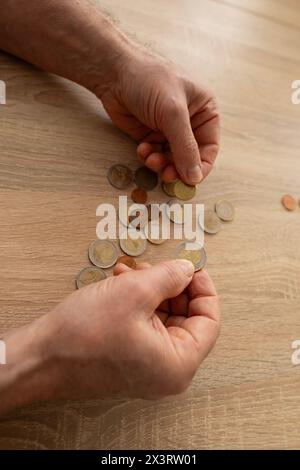 Povero pensionato, anziano stende monete da centesimo euro su tavola di legno, conta poco denaro contante sul tavolo, illustrando la dura realtà della vita in povertà Foto Stock