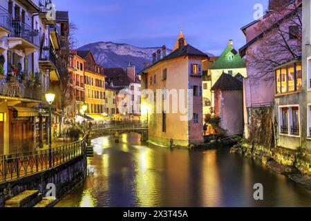 Scena notturna lungo il fiume Thiou ad Annecy, alta Savoia, Francia con Palais de l'Isle, un castello del XII secolo e le Alpi sullo sfondo. Foto Stock