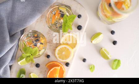 Cocktail estivi salutari di acque infuse di agrumi, limonate o mojito, con lime limone arancio mirtilli e menta, dieta detox bevande, in bicchieri Foto Stock