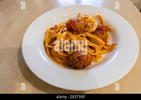 Piatto bianco di linguine con salsa di spaghetti e polpette sedute su un tavolo. Foto Stock