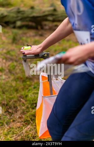 Una donna che pugni al punto di controllo dell'orientamento da vicino. Femmina in foresta che controlla un punto di controllo. Messa a fuoco selettiva Foto Stock