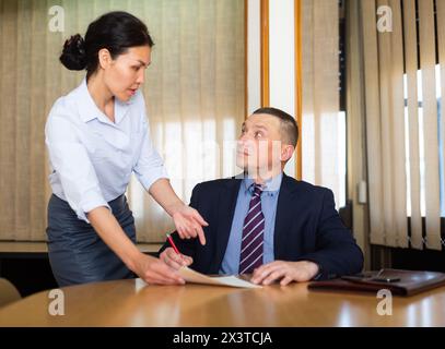 Documenti per la firma di uomini d'affari portati dalla partner femminile nella sala riunioni Foto Stock