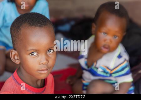 villaggio africano , bambini africani seduti davanti alla casa sul portico Foto Stock