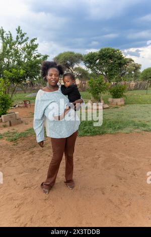 villaggio africano , famiglia africana madre e bambino in piedi davanti alla casa, madre che tiene il bambino Foto Stock